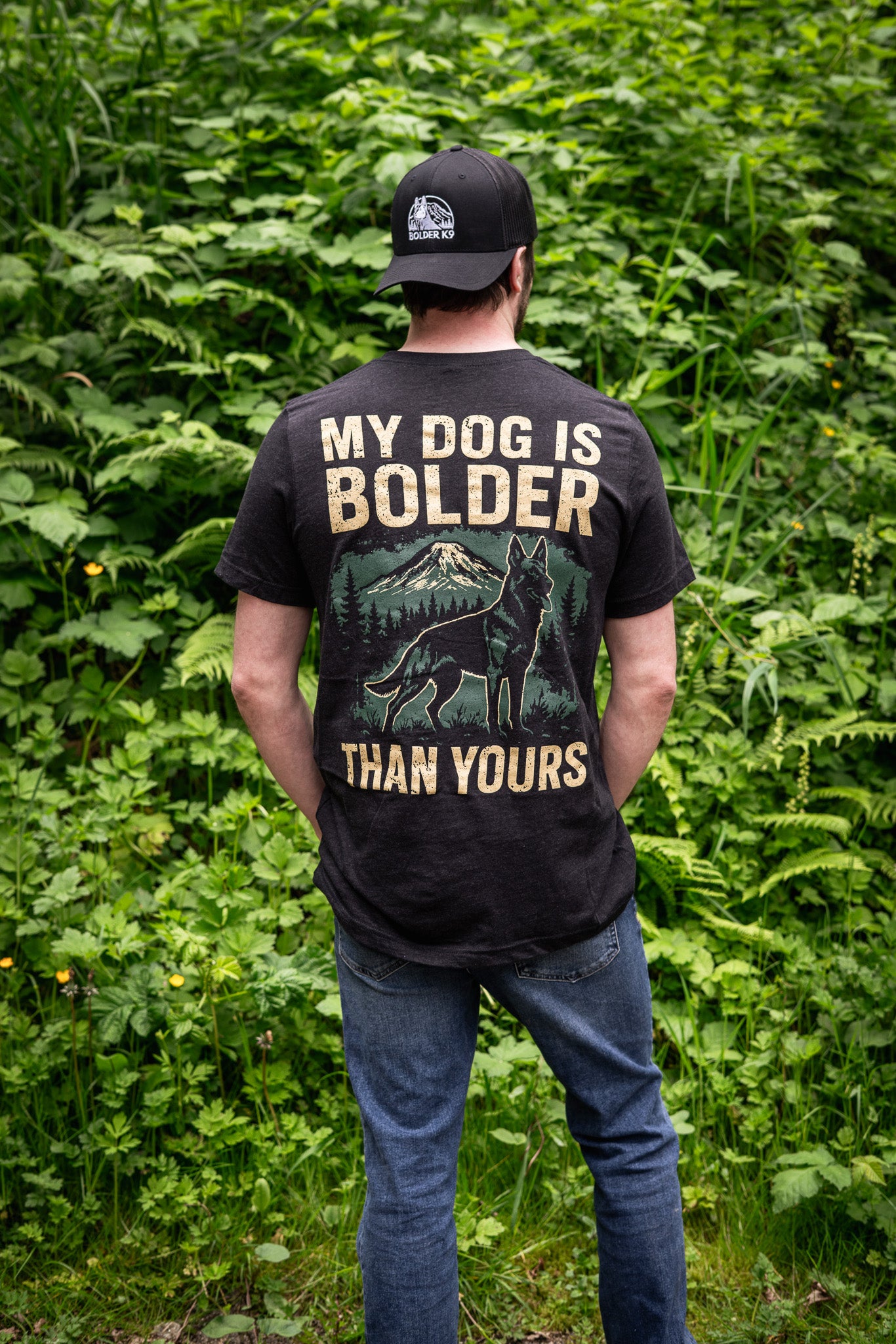 Person wearing 'My Dog Is Bolder Than Yours' t-shirt in a natural outdoor setting, showcasing the bold design.