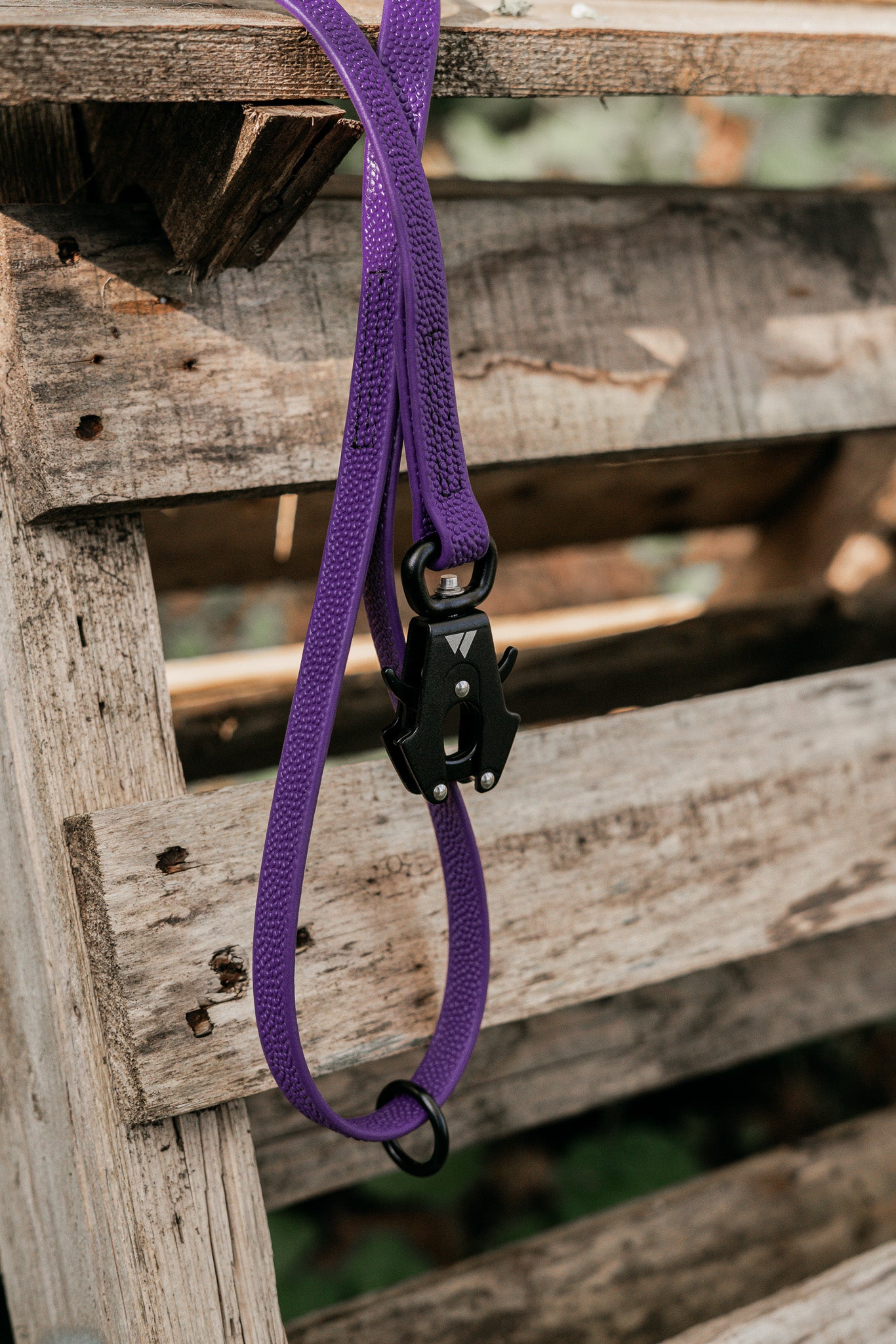 Purple Pebble Grip BioThane® leash hanging on a wooden pallet, showcasing its durable design and grip.