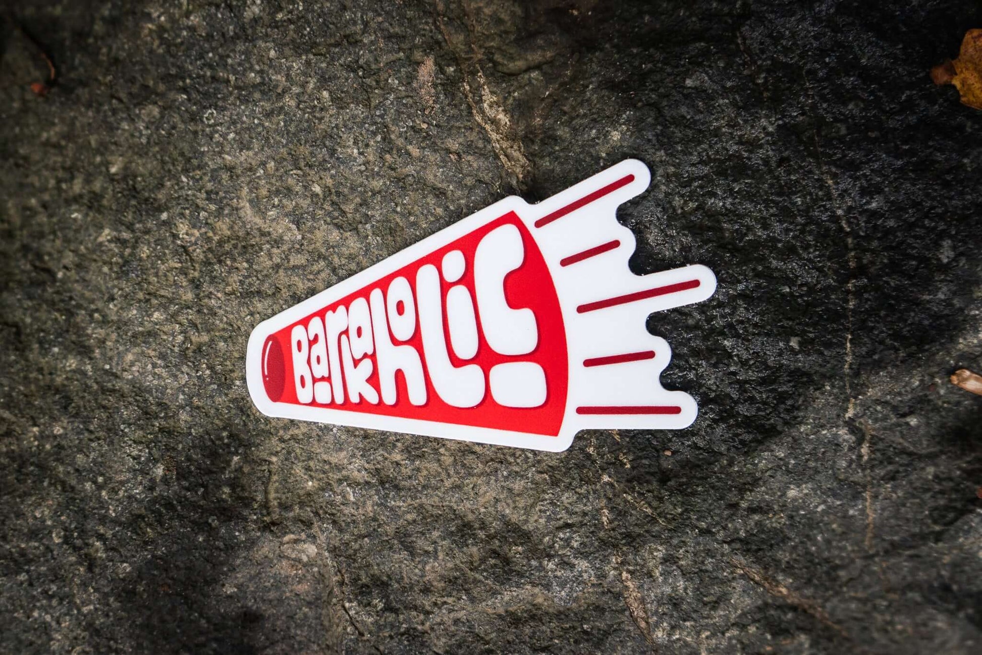 red sticker in the shape of a horn and inside it says barkaholic on a stone background