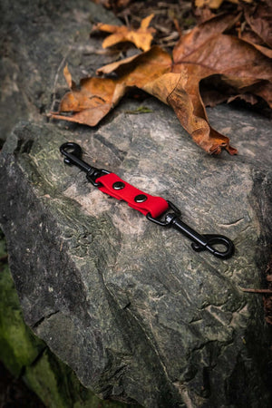 collar safety clip for dog collars in bright red biothane and double black clips on a stone background