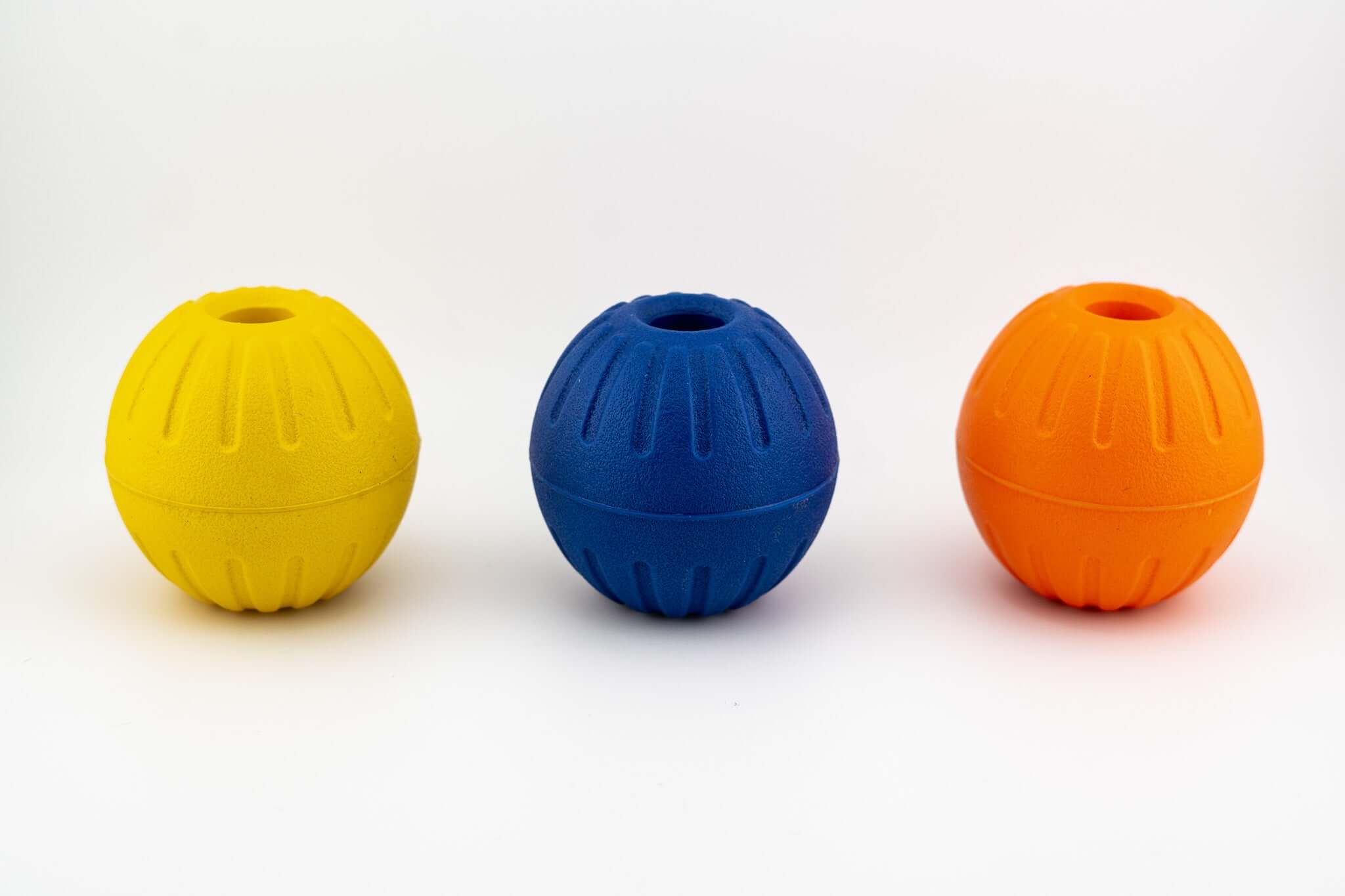 Durable EVA foam balls with center holes in yellow, blue, and orange for dog play and fetch.