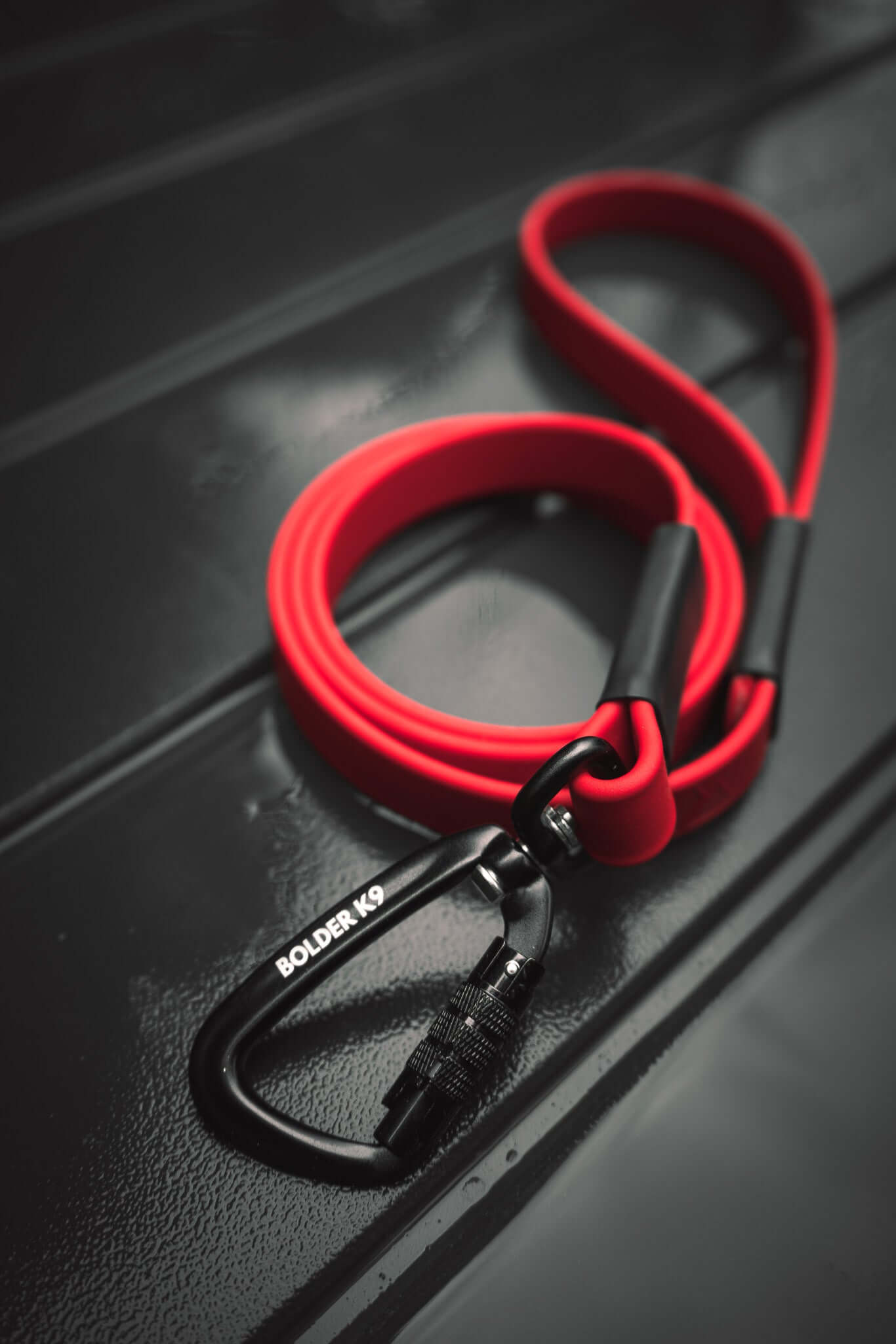 bright red biothane dog leash sewn with black carabiner on a dark background