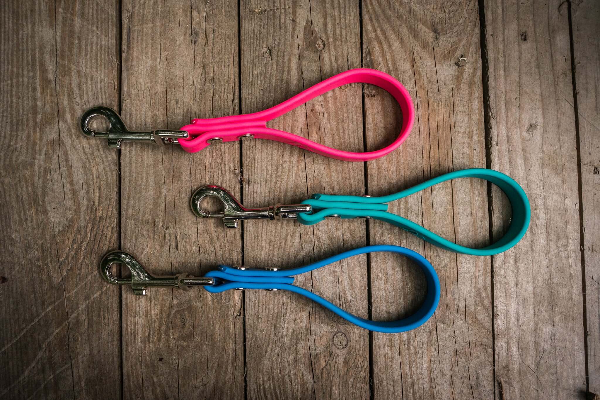 mini dog traffic leads three biothane color handles and silver clips on a wood background