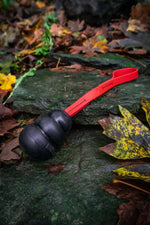 dog tug toy with a black kong toy on a bright red biothane rope on a background of leaves