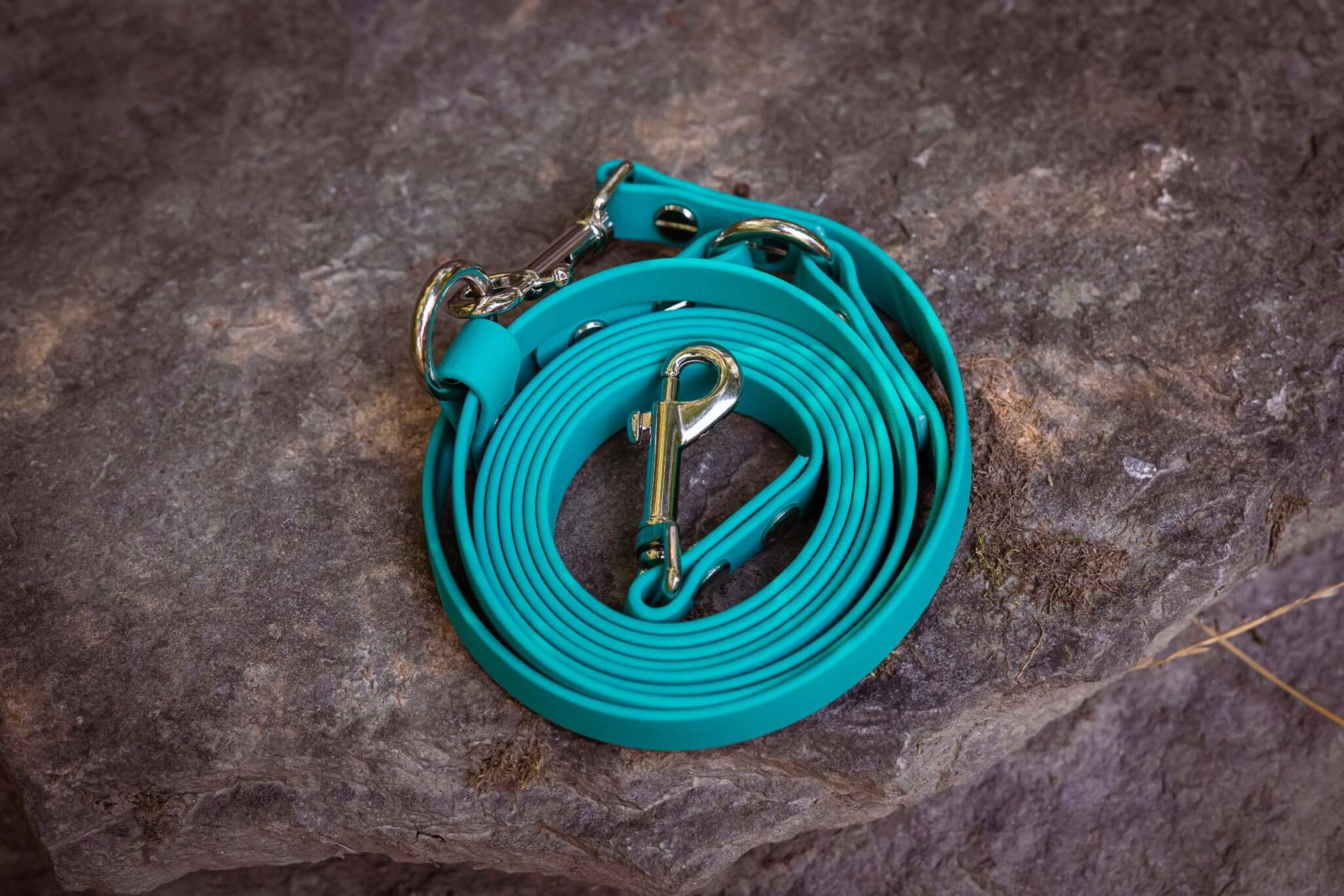 Aqua BioThane adjustable cross-body dog leash on rocky surface.