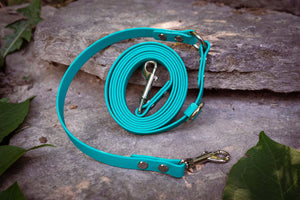 Aqua BioThane® adjustable cross-body dog leash on a stone surface, perfect for small dogs and light pullers, supporting dog rescue.