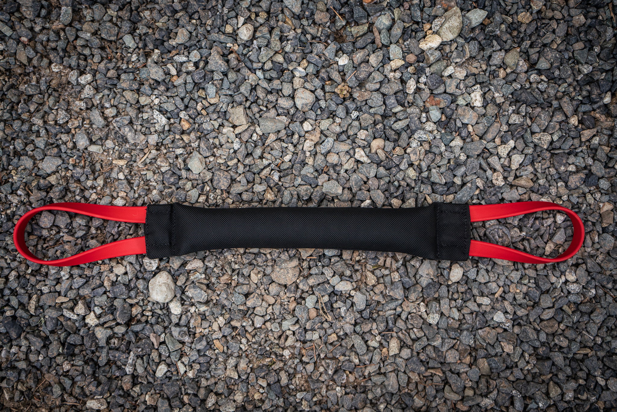 heavy duty bite tug with biothane handles on gravel background