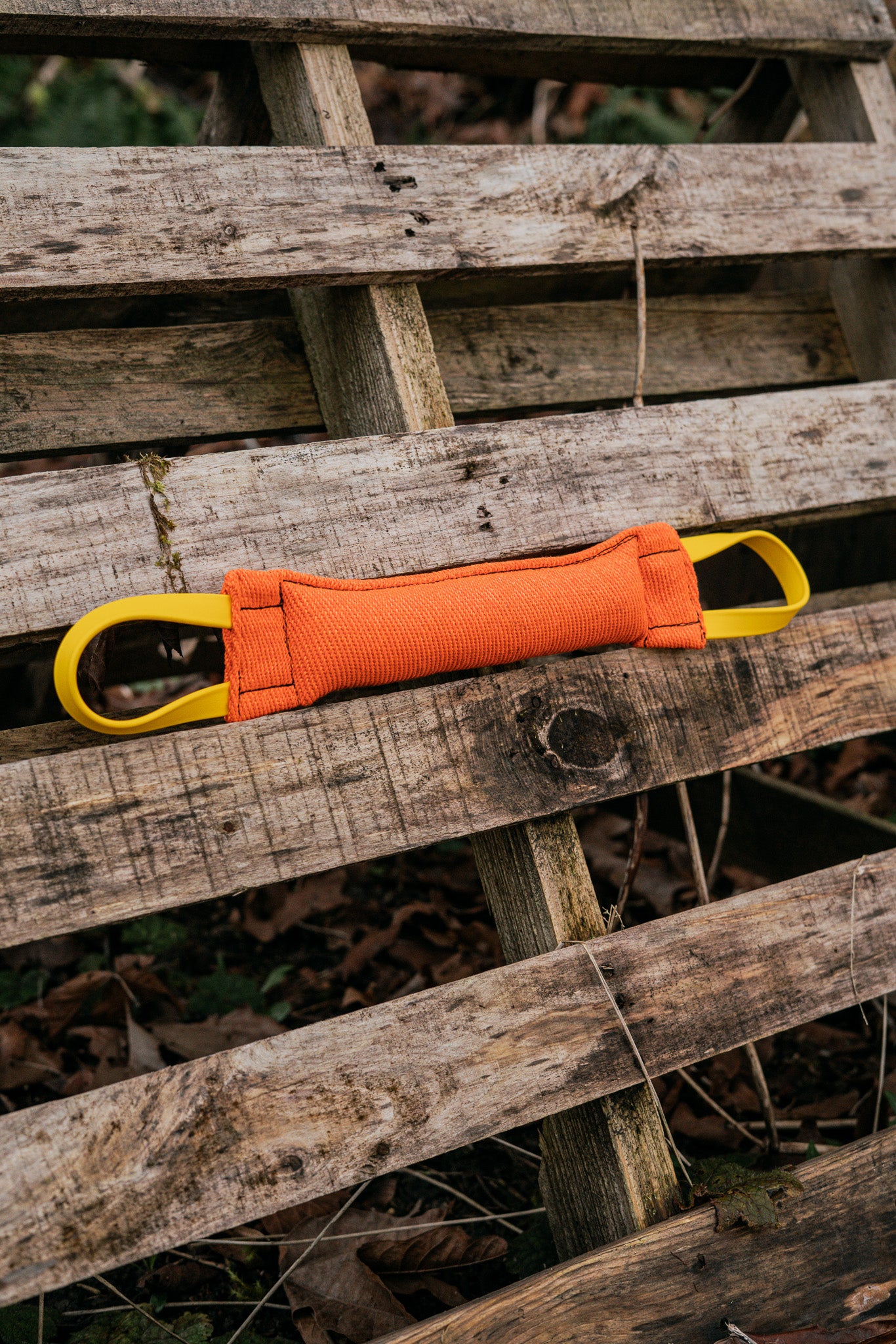 Reinforced bite tug with BioThane handles on wooden surface, perfect for dog training and play.