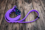 biothane dog leash in amethyst with black hardware and frog style clip on a wood background
